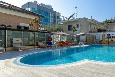 Piscina all'aperto con lettini e murale colorato in un hotel.